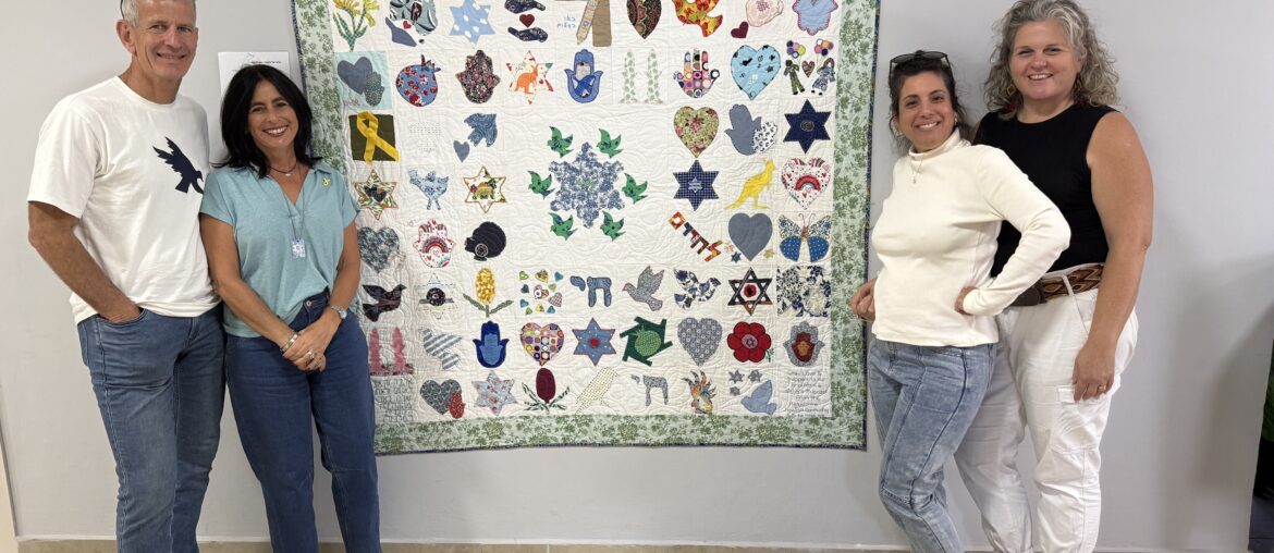 four people standing with a quilt named the quilt of hope
