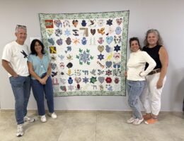 four people standing with a quilt named the quilt of hope
