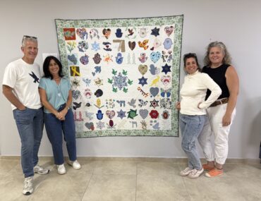 four people standing with a quilt named the quilt of hope